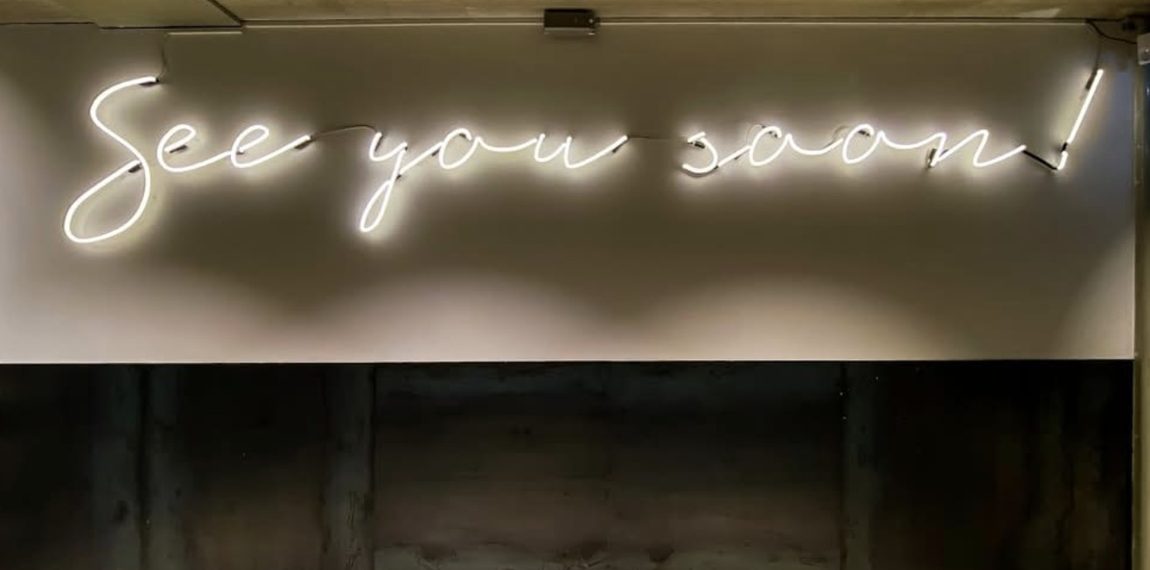 Neon sign reading see you soon inside Top Notch Beauty